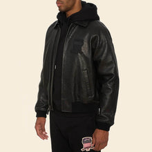 Load image into Gallery viewer, Person wearing a black leather jacket with a brand logo on a beige background