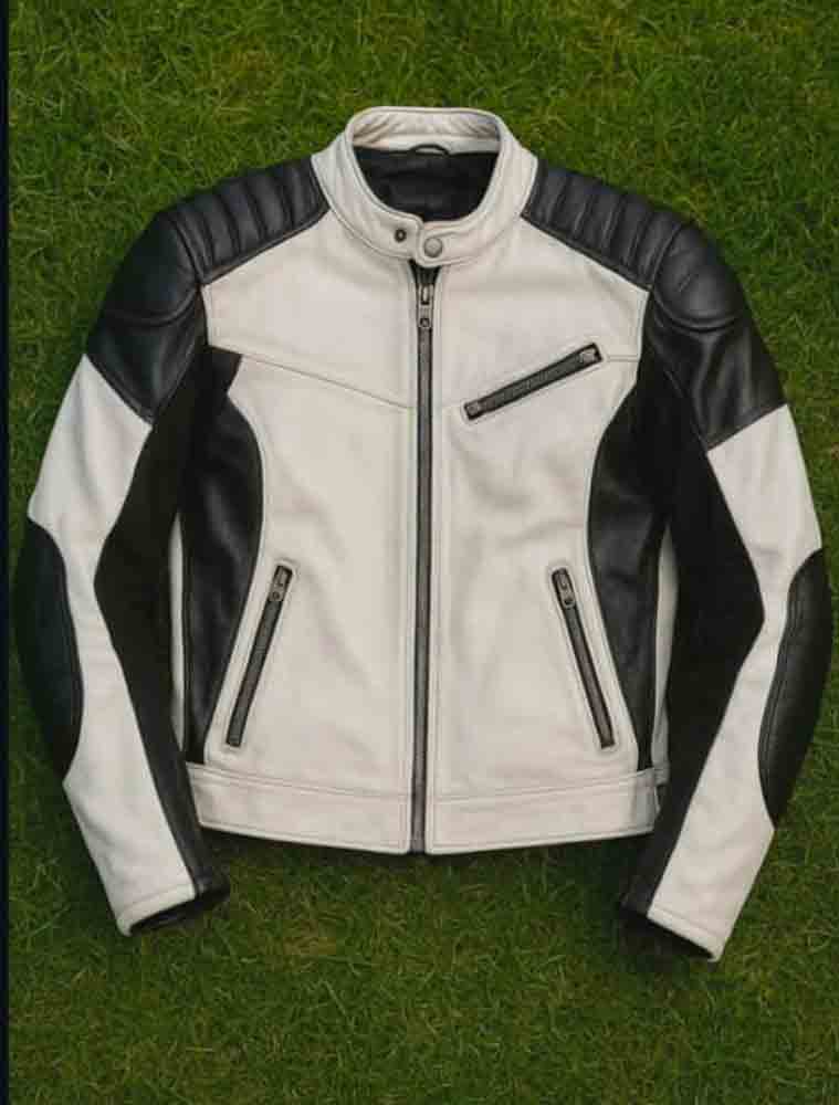 A black and white leather motorcycle jacket laid flat on green grass, featuring a white body with black leather shoulder panels, sleeves, and side sections, plus black zipper details.