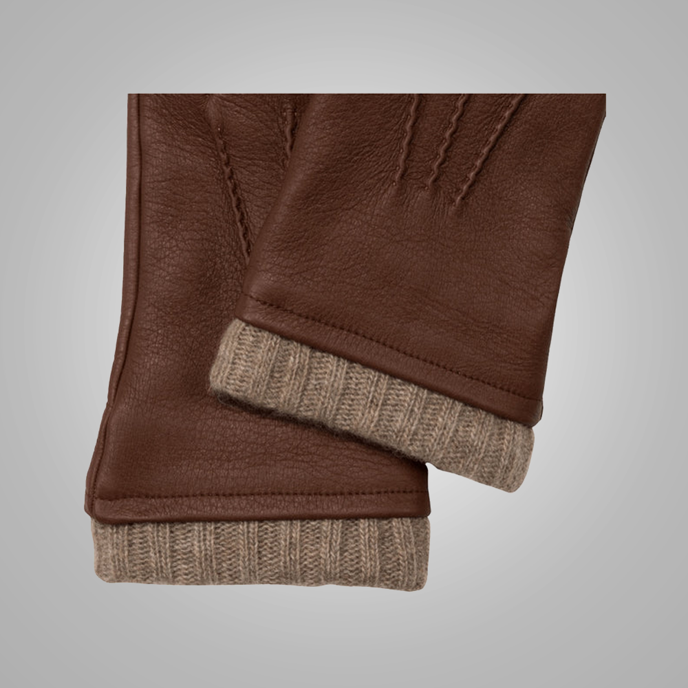 Folded brown leather gloves with beige lining on a gray background
