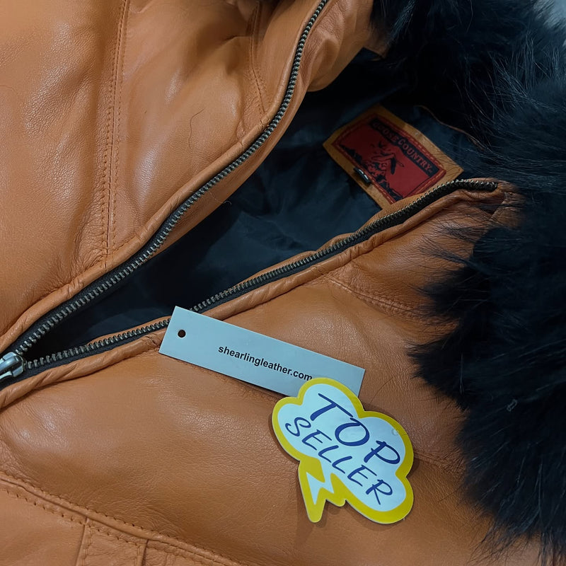 Close-up of a tan leather jacket with black fur trim, a black zipper, and a white hangtag reading shearlingleather.com.