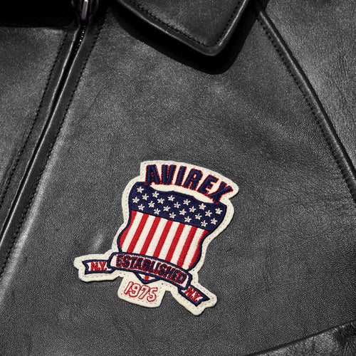 Close-up of a black leather jacket with a patch featuring an American flag design and 'Avirex' branding.