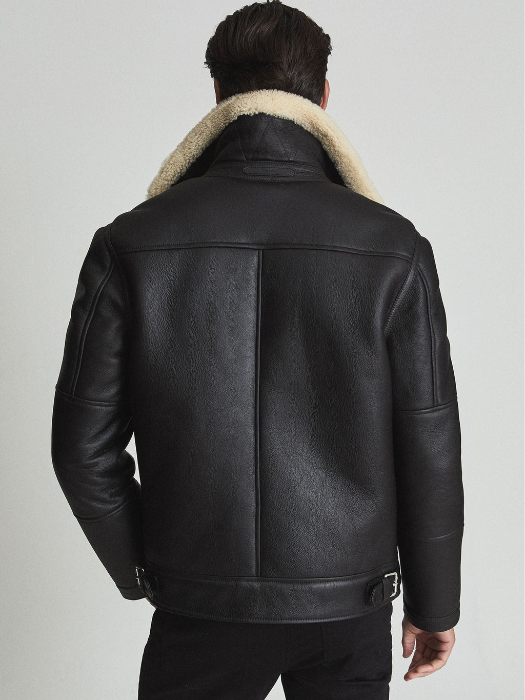 Back view of men’s black shearling biker jacket showing shoulder yoke, centre seam and adjustable waist buckles