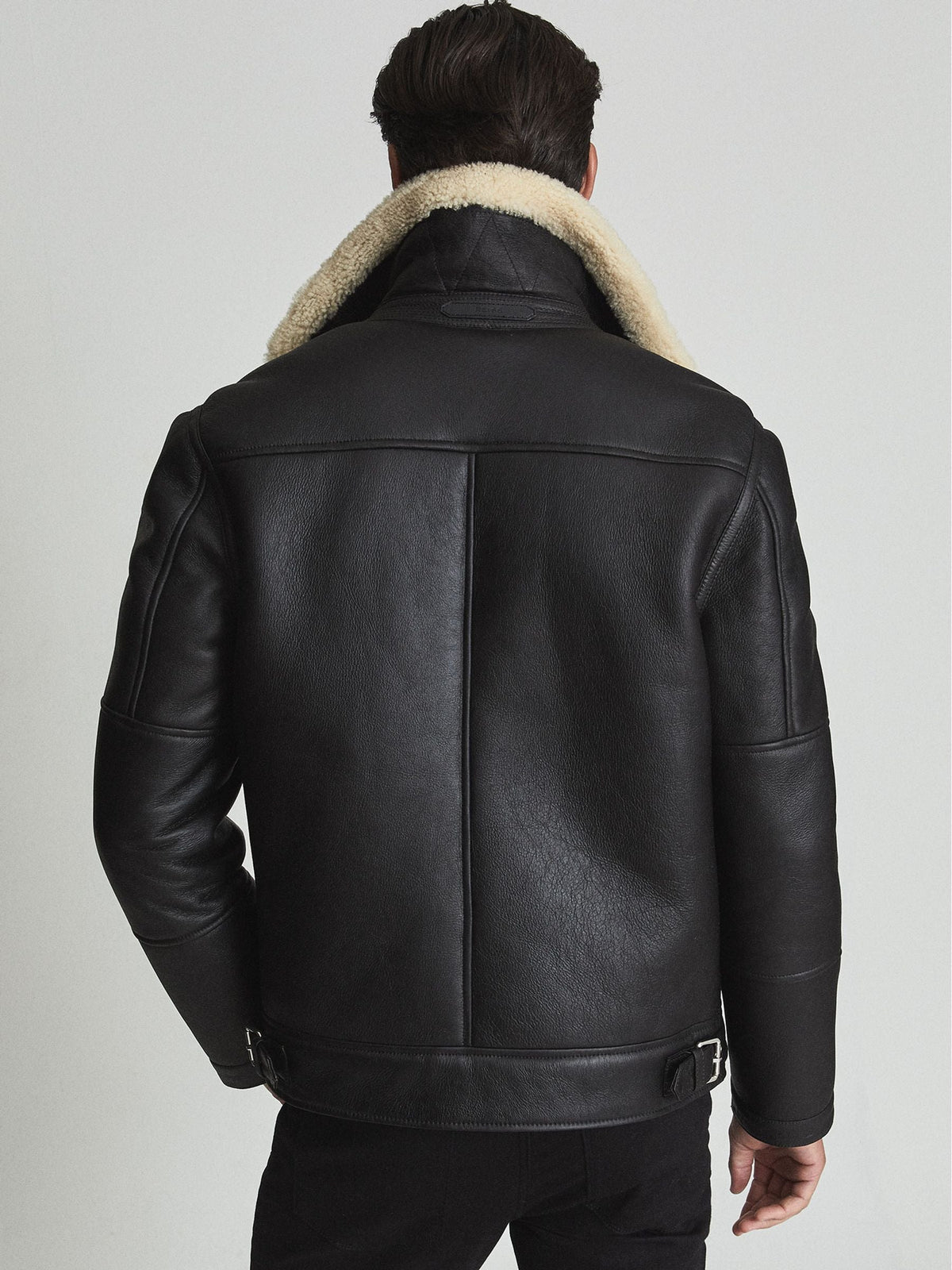 Back view of men’s black shearling biker jacket showing shoulder yoke, centre seam and adjustable waist buckles