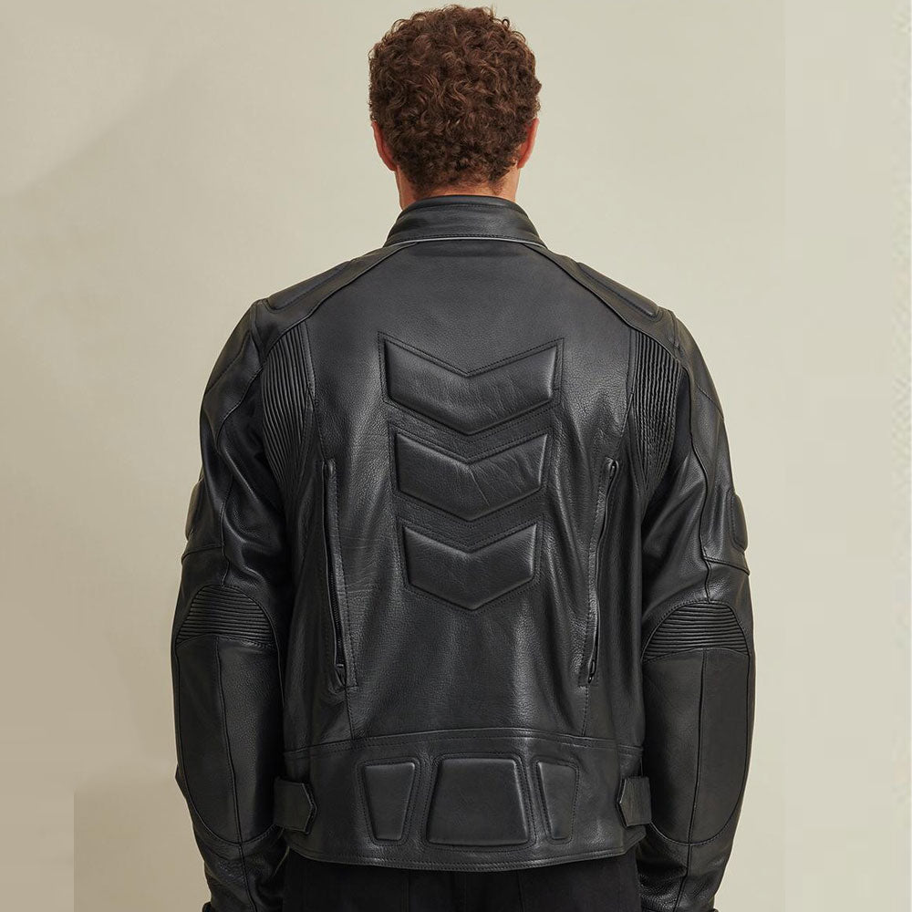 Person wearing a black leather jacket with a distinctive back design on a beige background
