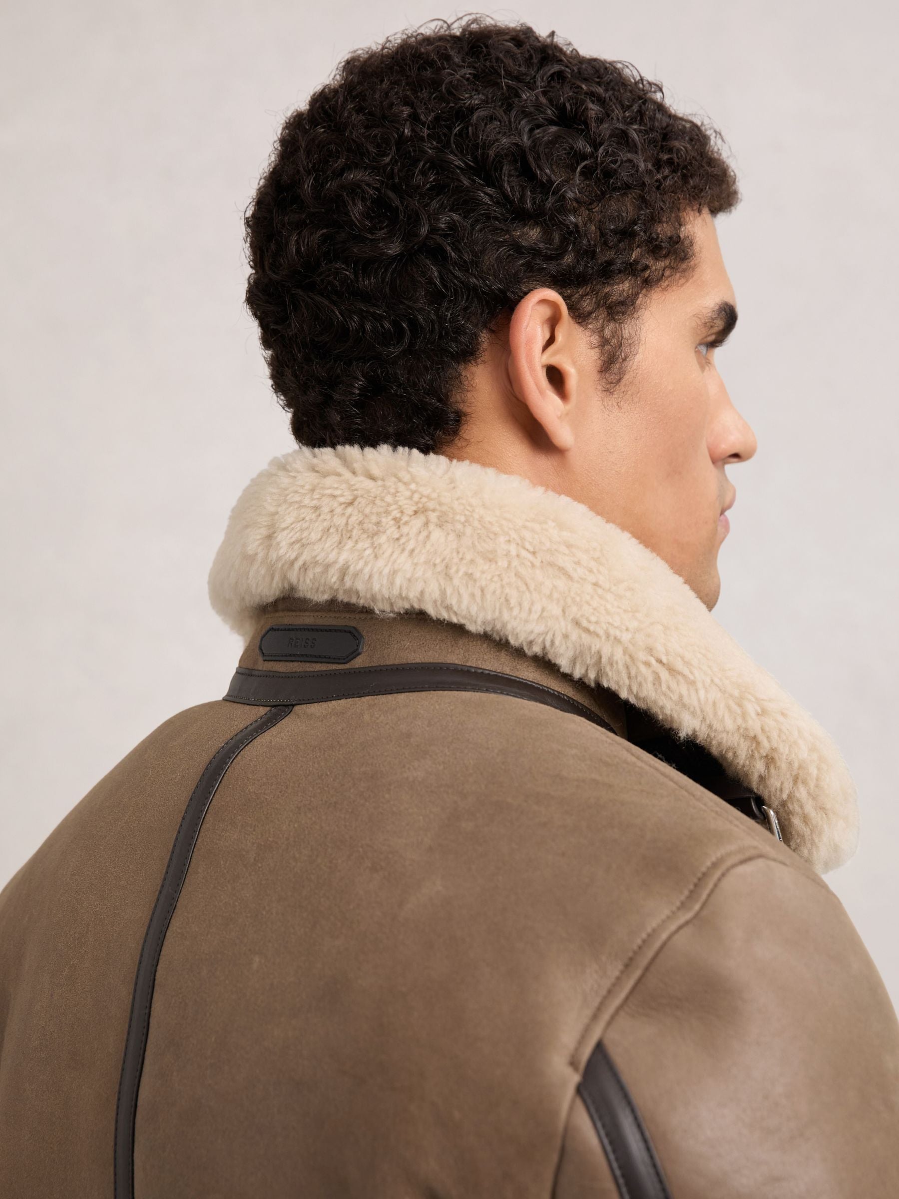 Rear collar and shoulder seam detail on light brown shearling jacket

