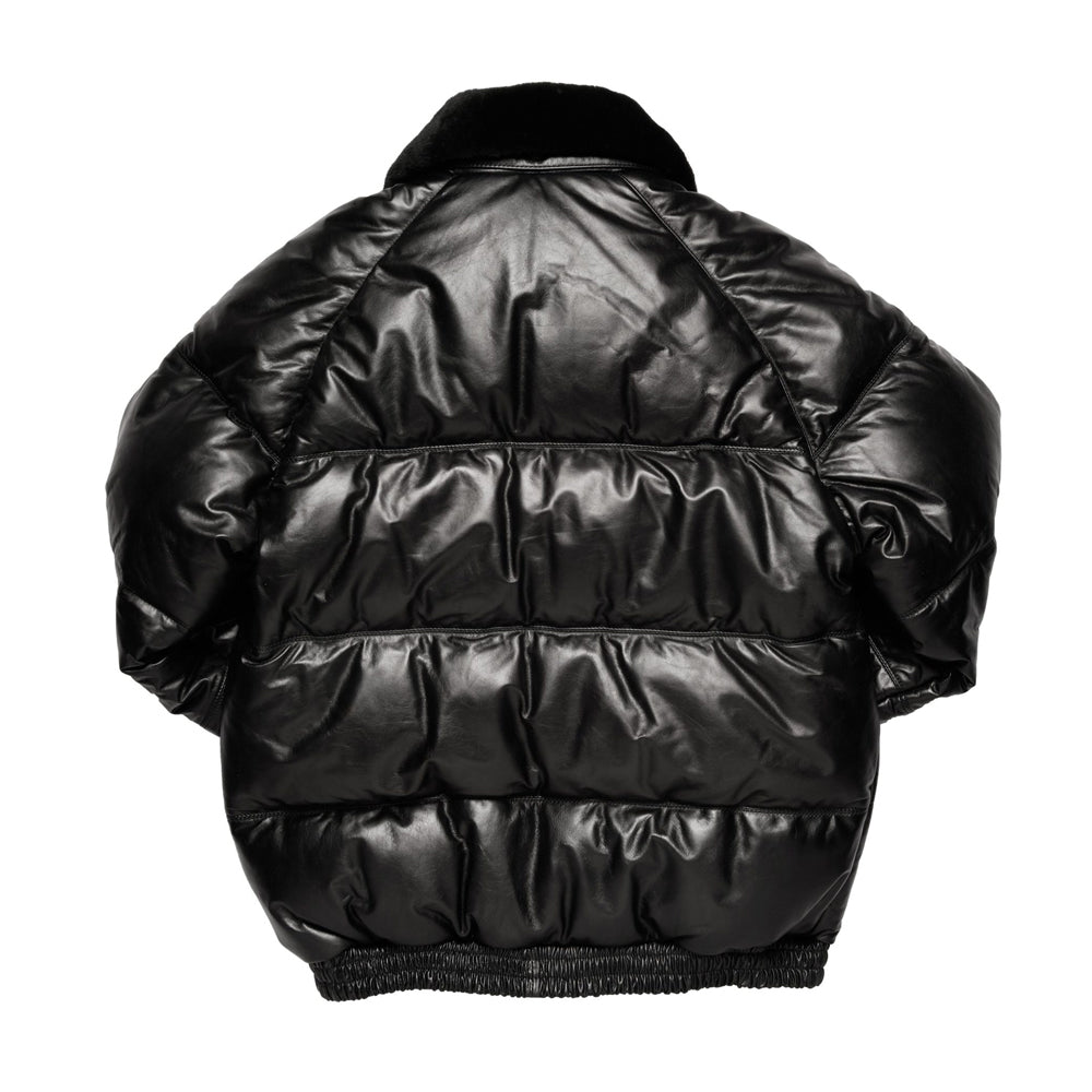 A black puffer jacket with horizontal quilting, a fuzzy black collar, and a ribbed black hem, shown from the back on a white background.