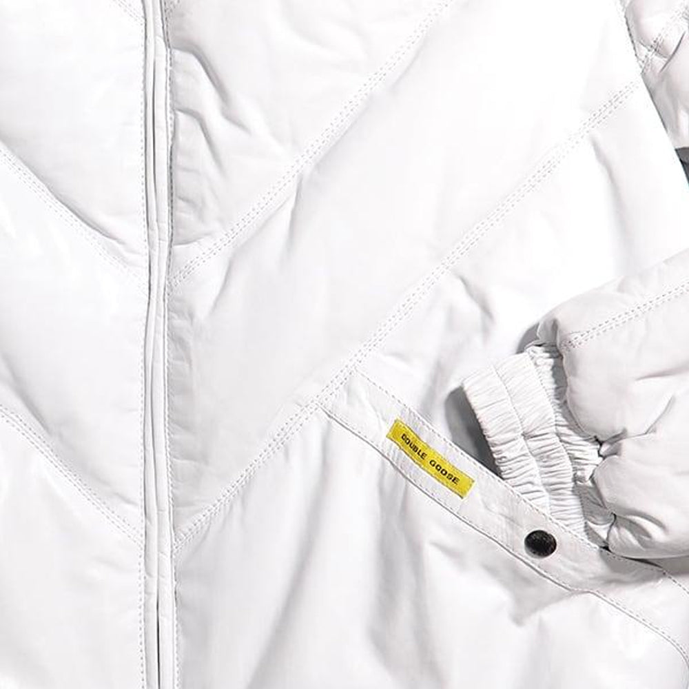 Close-up of a white quilted puffer jacket showing the diagonal stitching, a zippered front, and a small yellow brand tag near the cuff.