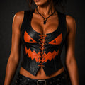 A woman wearing a black leather corset-style top with orange pumpkin-face details and orange laces, photographed against a dark studio background.