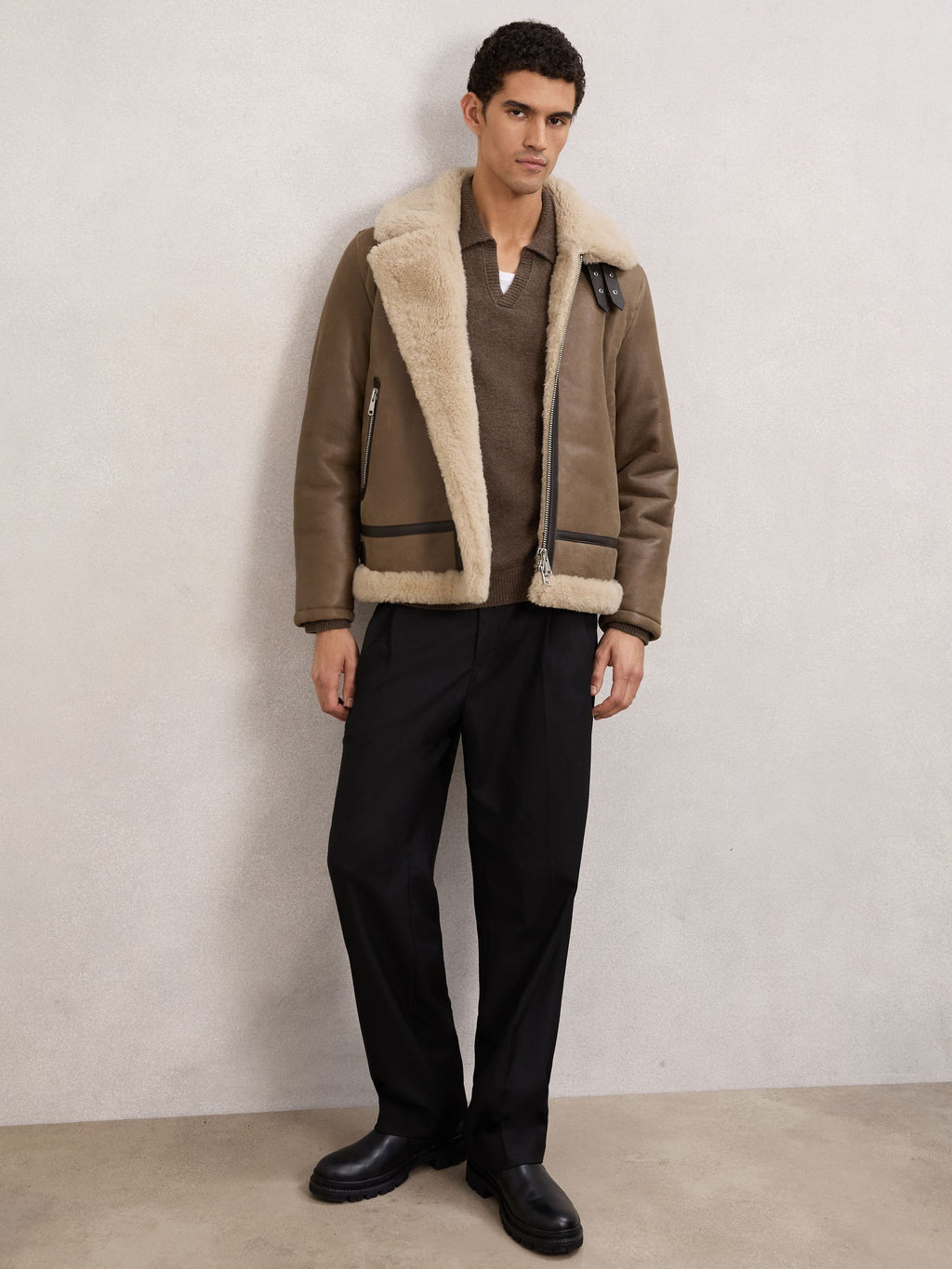 Full-length styling view of men’s light brown shearling bomber jacket