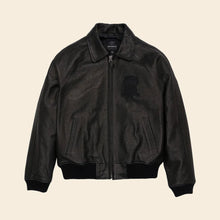 Load image into Gallery viewer, Black leather jacket on a beige background
