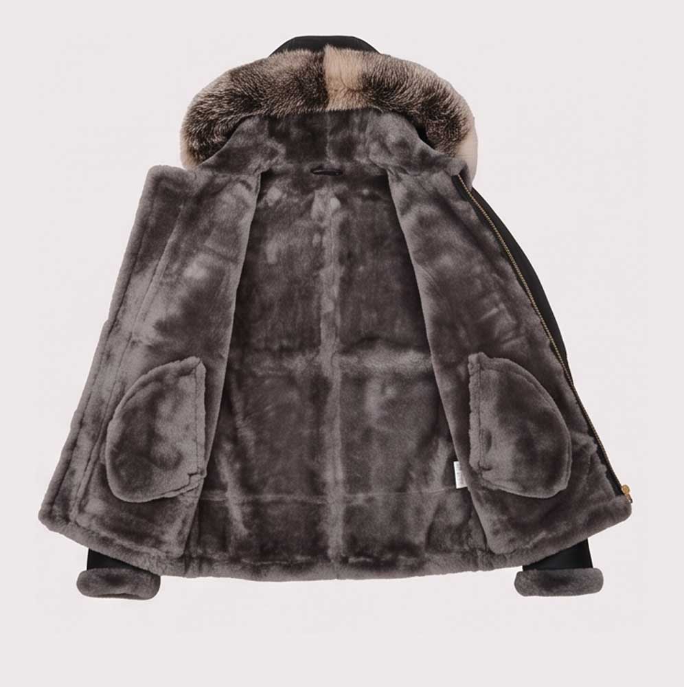 A dark gray faux fur jacket with a plush, shaggy texture, featuring a large brown and black fur-trimmed hood and two large front patch pockets, shown from the back against a light gray background.