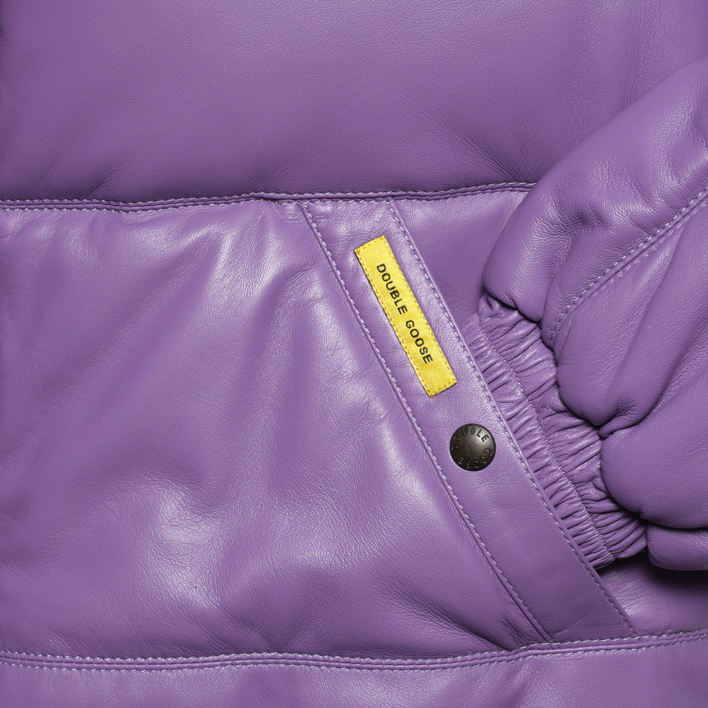 Close-up of a purple leather jacket detail showing a yellow 'DOUBLE GOOSE' brand tag, a black snap button, and an elasticized seam.
