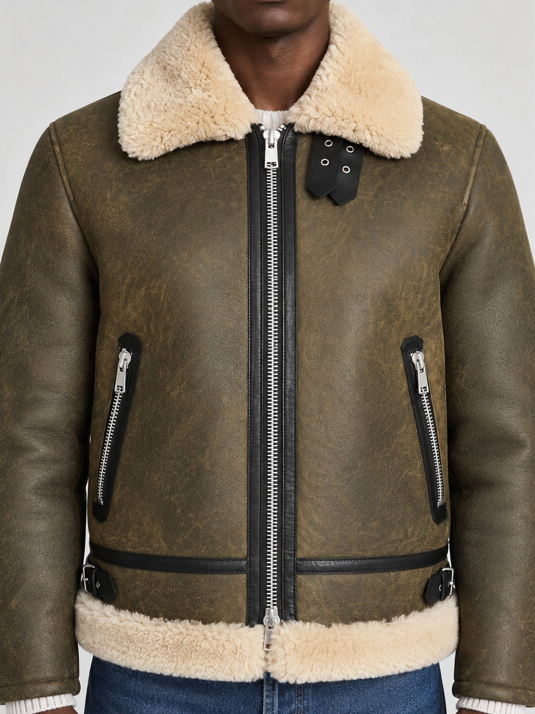 Close-up of army green shearling aviator jacket with cream collar, throat straps and silver zippers