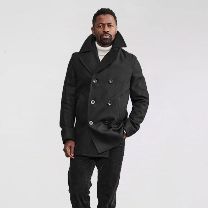 A man wearing a black wool peacoat with double-breasted button details, large lapels, and a V-neck collar.