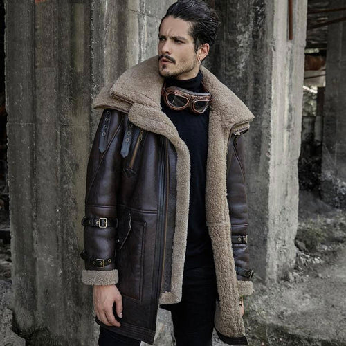 A man wearing a long brown shearling aviator fur coat with sheepskin leather and arm buckles.