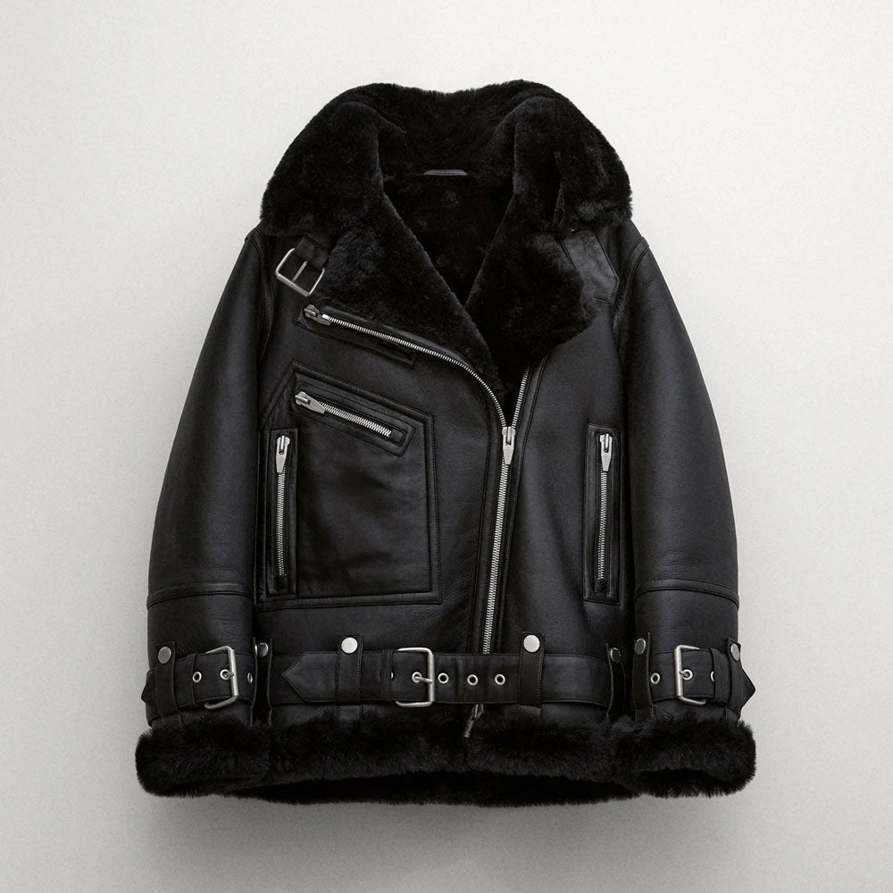 Black sheepskin shearling leather jacket with a standing collar, zippered front, and multiple belt straps.
